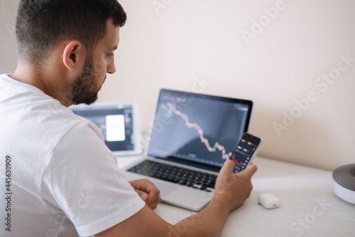Fototapeta Naklejka Na Ścianę i Meble -  Young adult man trading on line with tablet pc connected to stock market. People, finance, investments. Over the shoulders