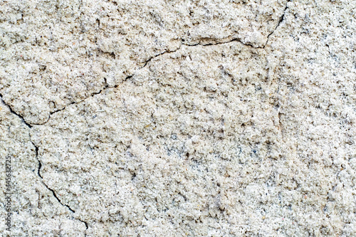 Concrete background. White old cracked stucco wall. Raised abstract texture. Damaged facade of building. Scuffed stone surface in grunge style. Table to shoot flat lay. Broken plaster. Copy space.