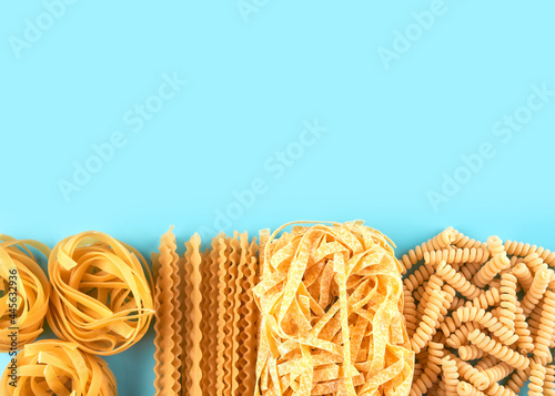 Assorted varieties of pasta wallpaper. Mix macaroni, spaghetti on blue background with copy space