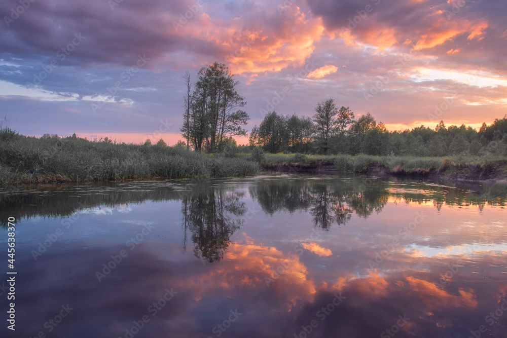 Summer scenery of the river and forest. Scenic sunrise over the river. Reflection clouds in the river.