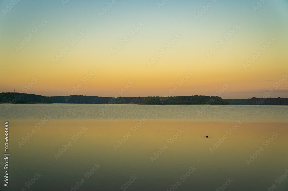 Calm beautiful sunrise over the lake with sky reflection in water