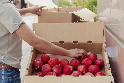 Shopper selecting stone fruit from a produce box