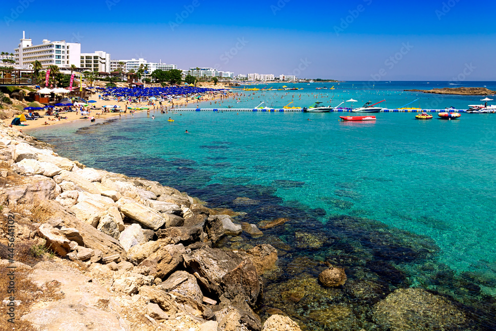 View of the sandy beach of Fig Tree Bay. The resort village of Protaras in Cyprus. Azure Mediterranean Sea. Tourists sunbathe and swim in the distance.