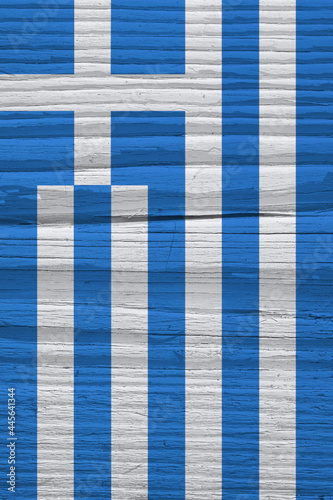 Flag of Greece on dry wooden surface, cracked with age. Vertical background, wallpaper or backdrop with Greek national symbol. It seems to flutter in the wind. Hard sunlight with shadows on old wood
