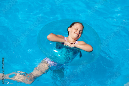 a six-year-old girl enjoys a swimming pool, an inflatable circle, summer and a family vacation. 