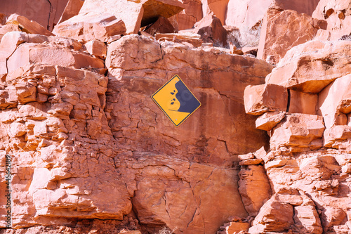 A beware of falling rocks sign posted to a cliff of red rocks in Utah