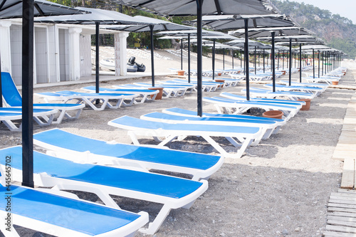 Resort beach with empty sun loungers. Vacation at sea. Sun loungers