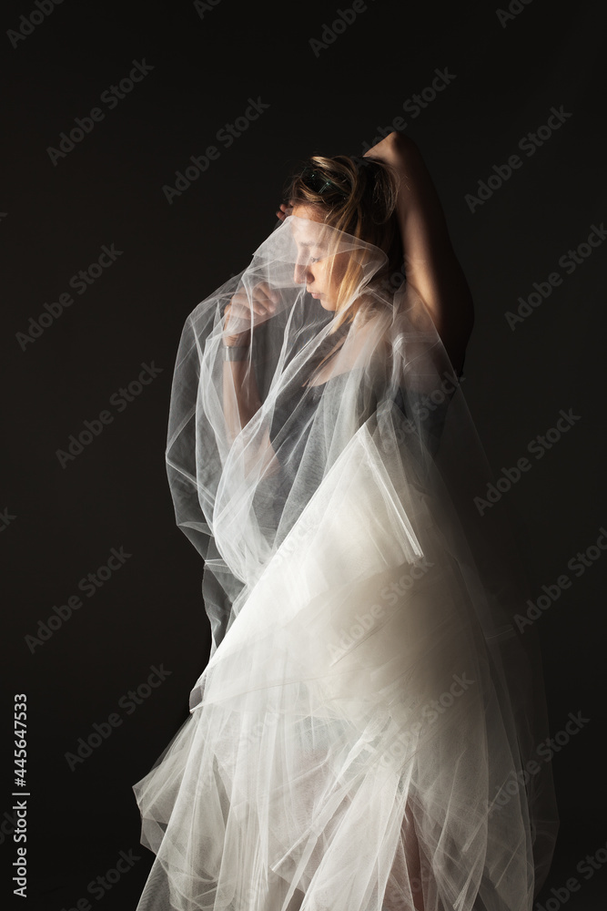 Fototapeta premium ballerina with a white dress and black top posing on gray background.