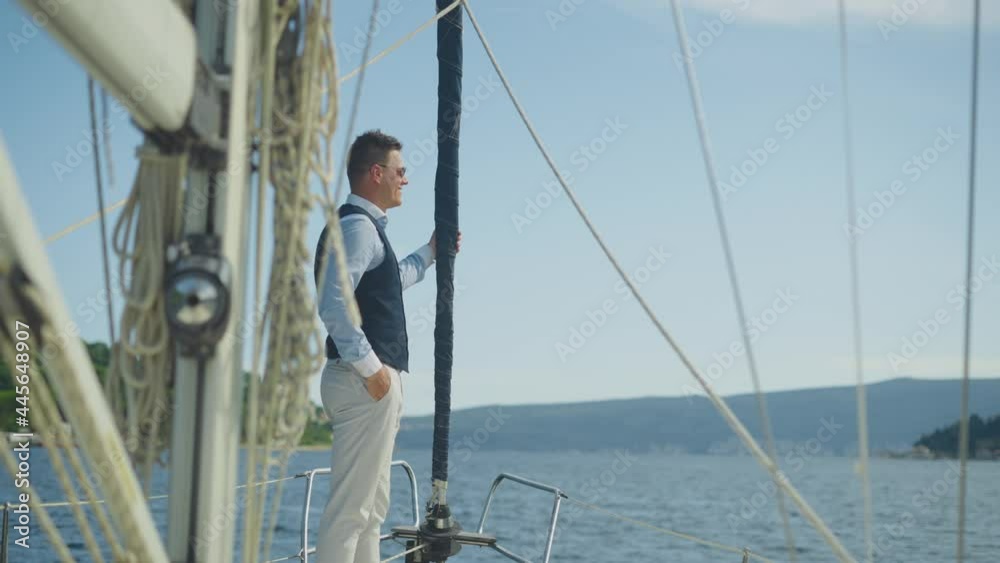 Smiling mid adult man standing on yacht deck and looking away. Summer vacation at sea, sailing and travelling concept. Smiling mid adult man standing on yacht deck and looking away. Summer vacation at sea, sailing and travelling concept.
