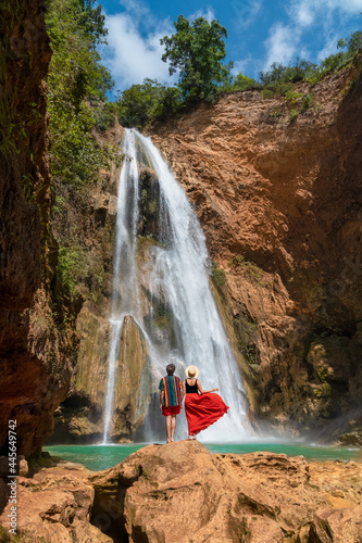 Fototapeta Naklejka Na Ścianę i Meble -  Couple holding hands in waterfall, rear views. Couple admiring a beautiful waterfall in Oaxaca. Couple on vacation in Mexico. Honey moon trip. Apoala Oaxaca waterfall