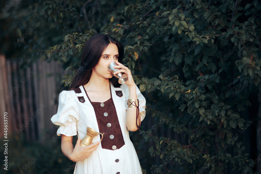 Woman Drinking from a Metal Cup holding a Pitcher with Wine Woman Drinking from a Metal Cup holding a Pitcher with Wine