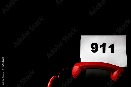 Emergency call concept, the text 911 on paper and telephone isolated on black background photo