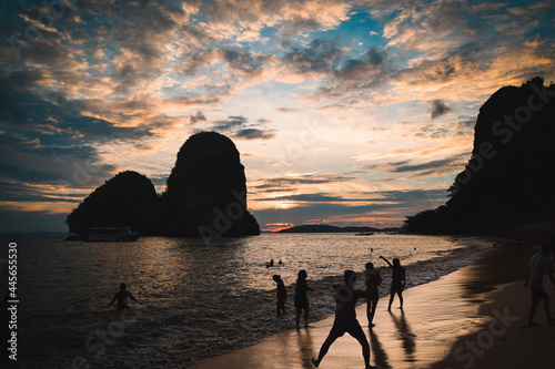 Sunset in Railay Beach  Thailand. People swimming and playing during the susent. Boat arriving to the coast. People silhouette.