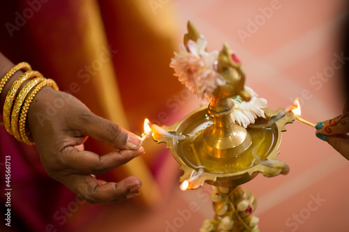 Woman lighting a traditional brass oil lamp during a Hindu wedding celebration photo