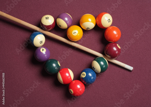 Photography Pool cue stick bisecting heart-shaped cue balls on billiard table