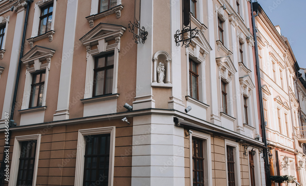 An old beautiful building with windows and decorative fittings and a sculpture of the Virgin Mary and Child in a niche. Lviv, Ukraine.