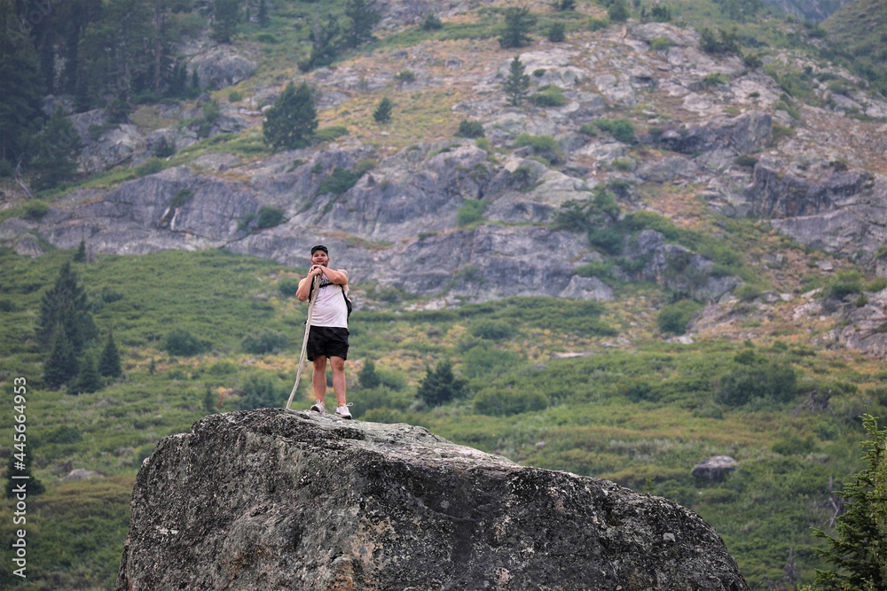 A Hiker Standing Atop a Large Rock Outcrop Beneath the Mountains in the Grand Teton National Park