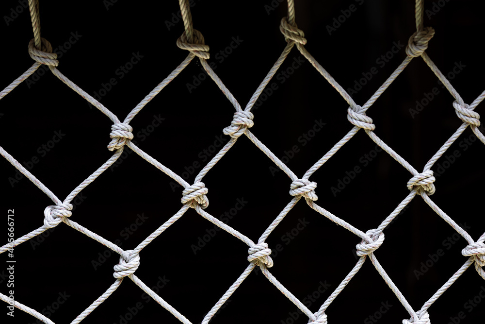 Fototapeta premium White net with dark background showing repeated pattern of weaving and knots