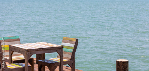 Open cool corner wooden dining table next to a local pier with sea background
