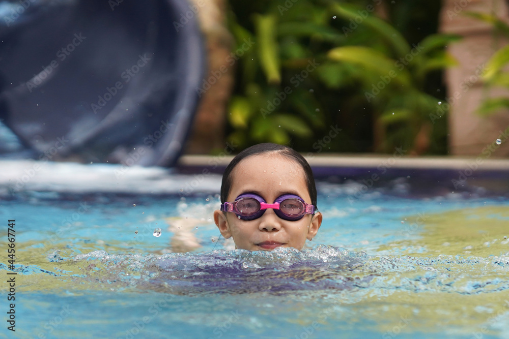 Little girl having fun while enjoying swimming in a pool. Summer concept.