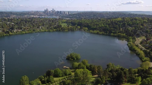 Flying Left to Right With A City on the Horizon Set Against a Lake - Green Lake Seattle