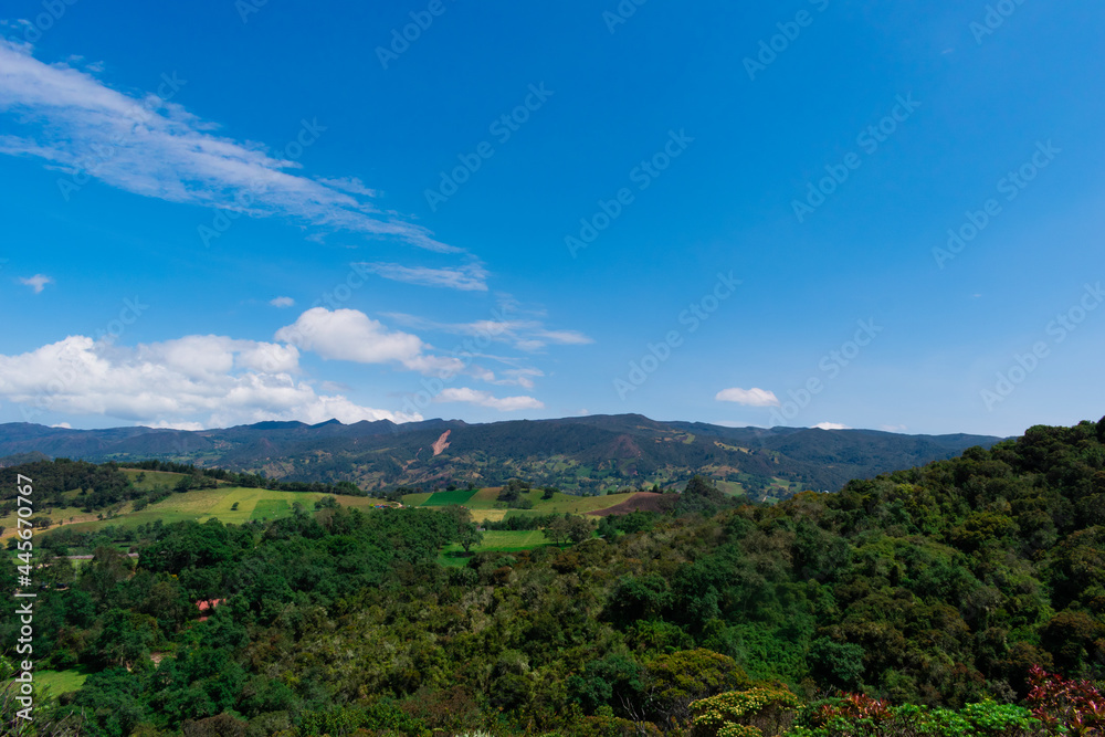 Landscape of mountains, country houses and crops with a blue sky and some clouds in Colombia.