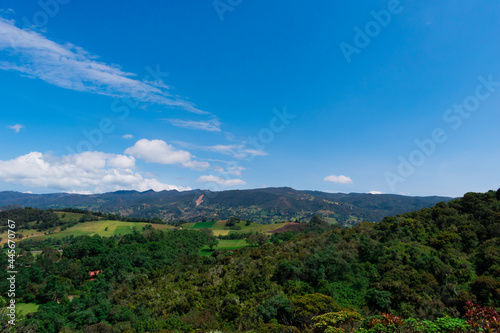 Landscape of mountains  country houses and crops with a blue sky and some clouds in Colombia.