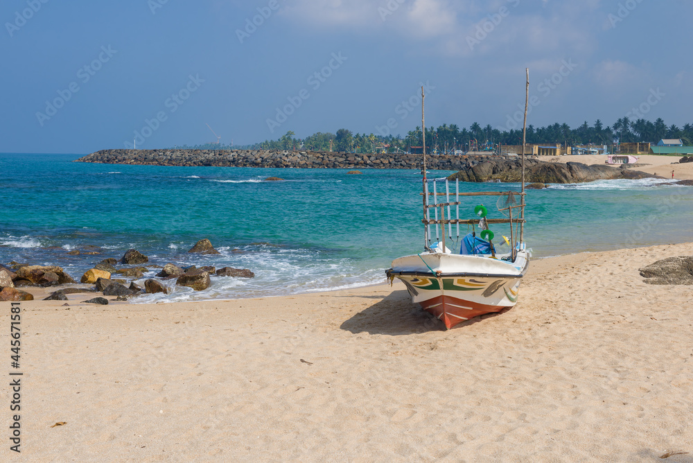 Fishing boat on the ocean shore on a sunny day. Ambalangoda, Sri Lanka Fishing boat on the ocean shore on a sunny day. Ambalangoda, Sri Lanka