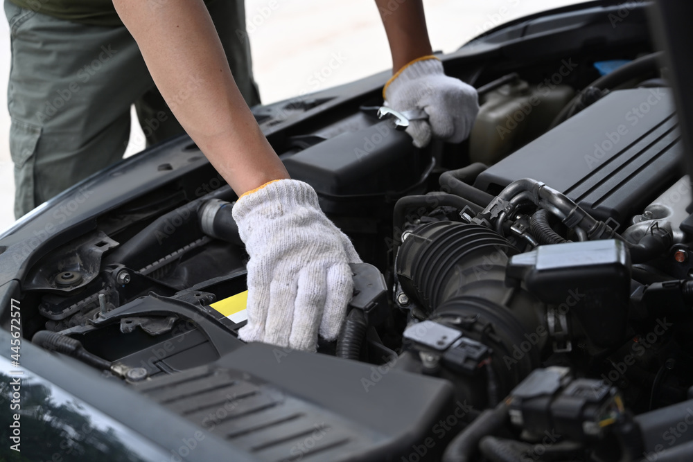 Cropped shot mechanics working on car engine in mechanics garage.