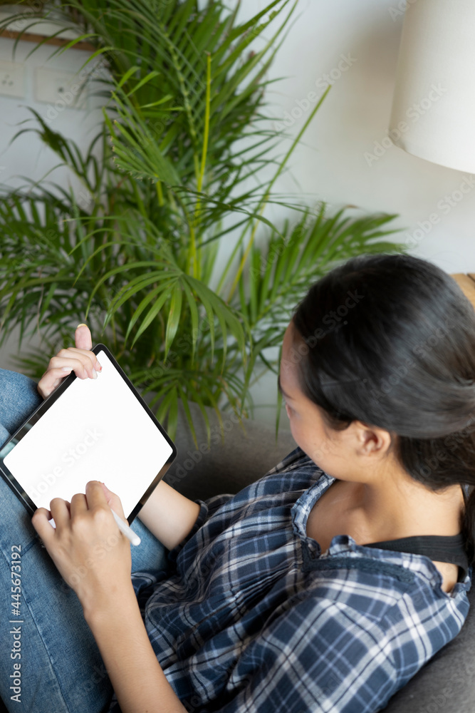Female freelancer holding stylus pen and working with digital table at home.