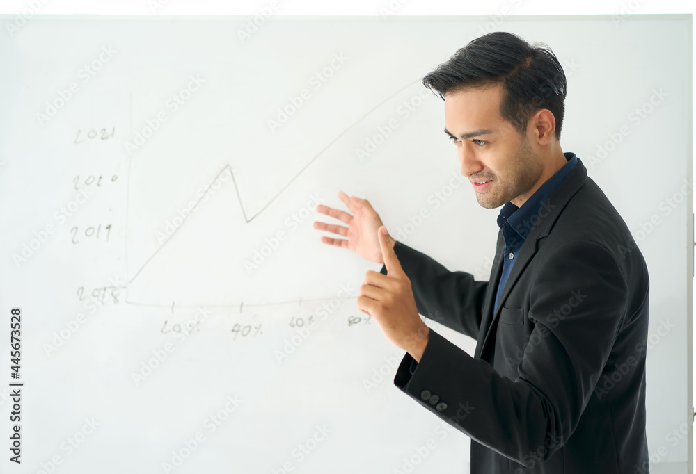 Businessman presenting profitable plan standing next to whiteboard with sales line graph Businessman presenting profitable plan standing next to whiteboard with sales line graph