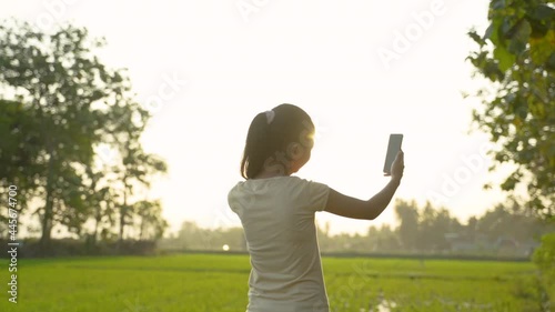 portrait of a beautiful young girl looking while holding a cellphone take a selfie on sunset photo