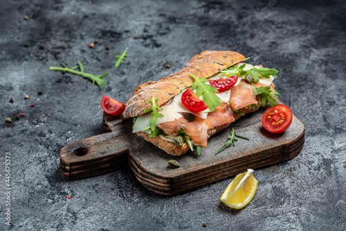 Ciabatta burger sandwich with salmon, parmesan cheese, capers, cherry tomatoes and arugula, banner, menu recipe place for text, top view