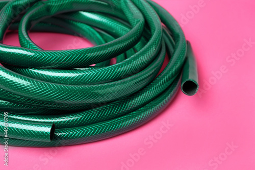 Watering hose on pink background, closeup view