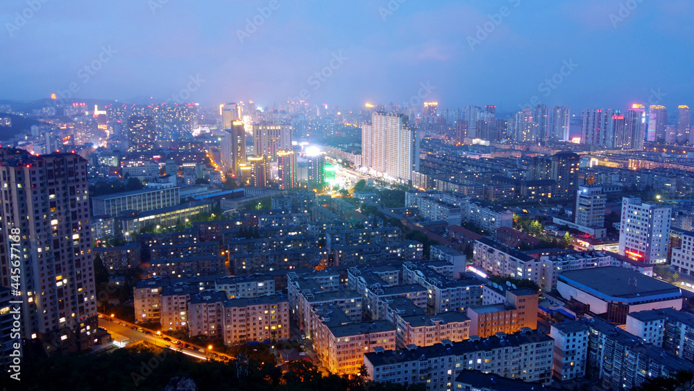 Pretty night scene of a city with tall buildings, brightly lit. High-angle shot