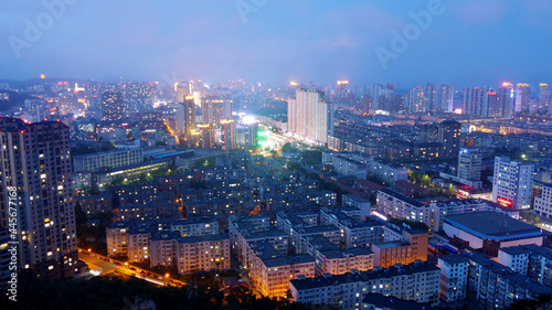 Pretty night scene of a city with tall buildings  brightly lit. High-angle shot