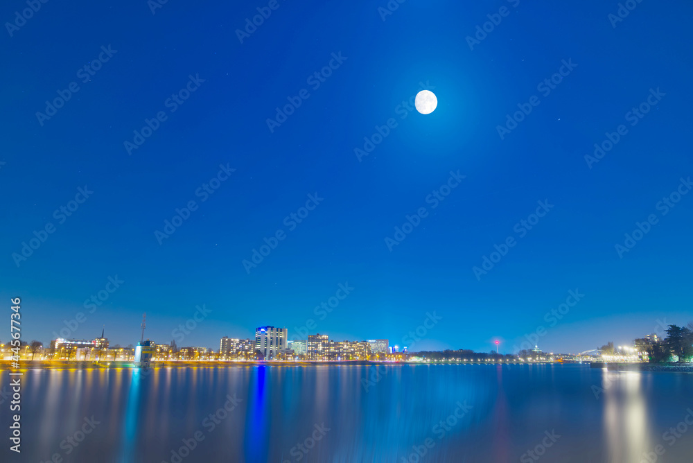 Rotterdam in the Netherlands under the moonlight, with brilliant and colorful lights reflecting on the river, a beautiful night view