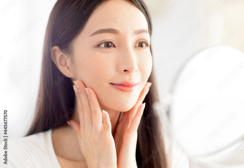 Beautiful Young woman touching face skin and looking in mirror Beautiful Young woman touching face skin and looking in mirror