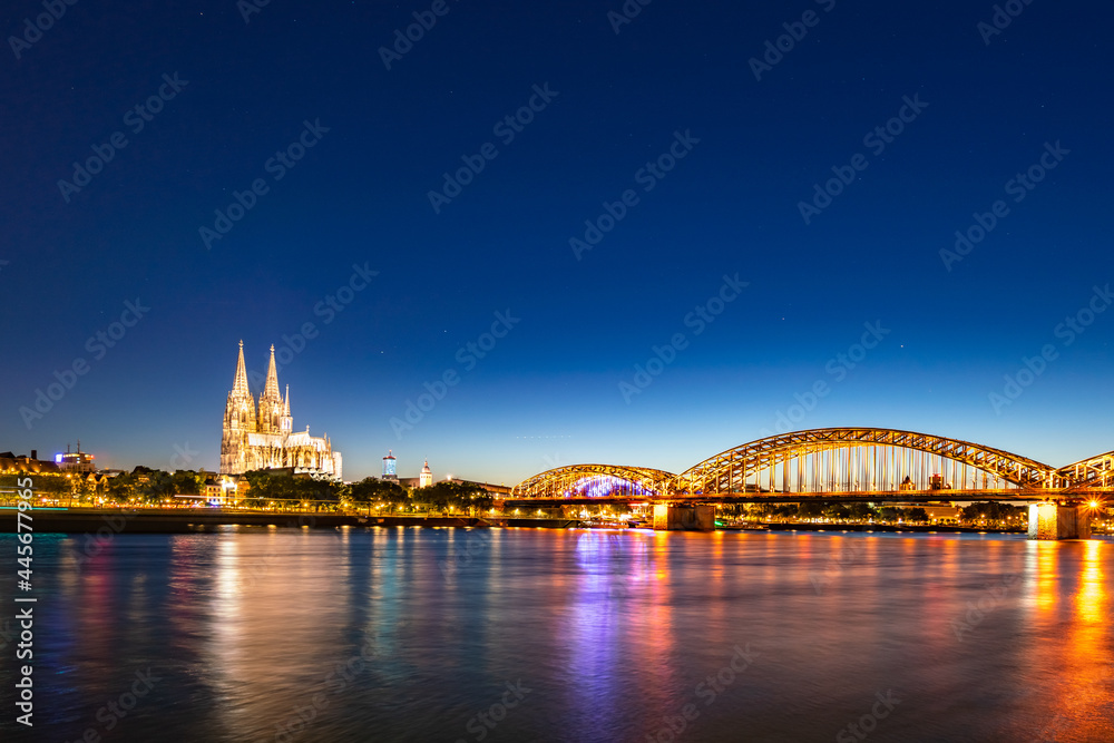 In Cologne, Germany, the river is shining brightly with the light at night, a beautiful bridge. Long shot In Cologne, Germany, the river is shining brightly with the light at night, a beautiful bridge. Long shot