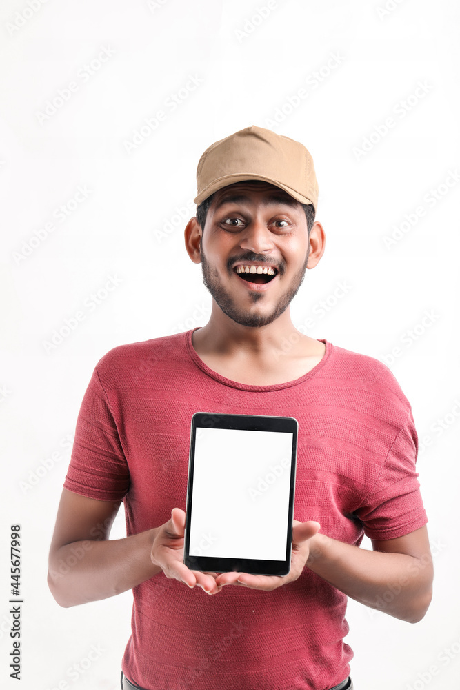Portrait of a excited happy young delivery man in cap standing over white background. Looking camera showing display of mobile phone. Portrait of a excited happy young delivery man in cap standing over white background. Looking camera showing display of mobile phone.