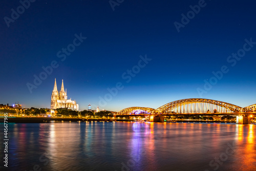 In Cologne, Germany, the river is shining brightly with the light at night, a beautiful bridge. Long shot