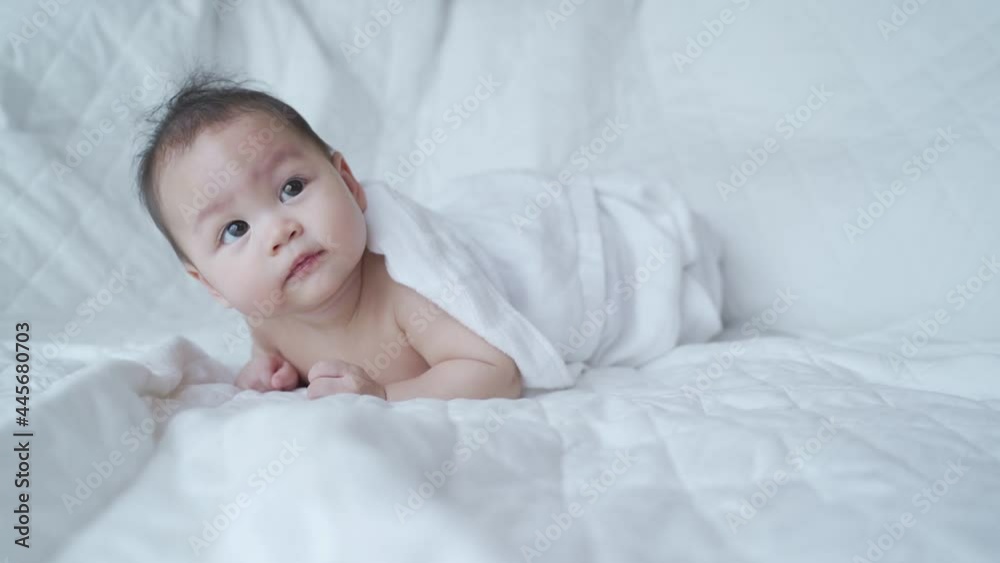 portrait of asian baby infant 6 months old naked after bathing covered with white towel. happy innocence baby kid sitting and crawling on bed. sucking hand age baby portrait copy space provided. portrait of asian baby infant 6 months old naked after bathing covered with white towel. happy innocence baby kid sitting and crawling on bed. sucking hand age baby portrait copy space provided.