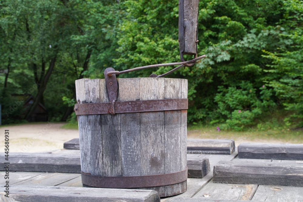 old wooden bucket standing on the lid of a village well 