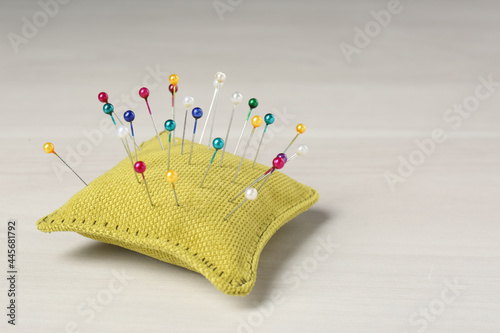 Yellow cushion with pins on white table. Space for text photo