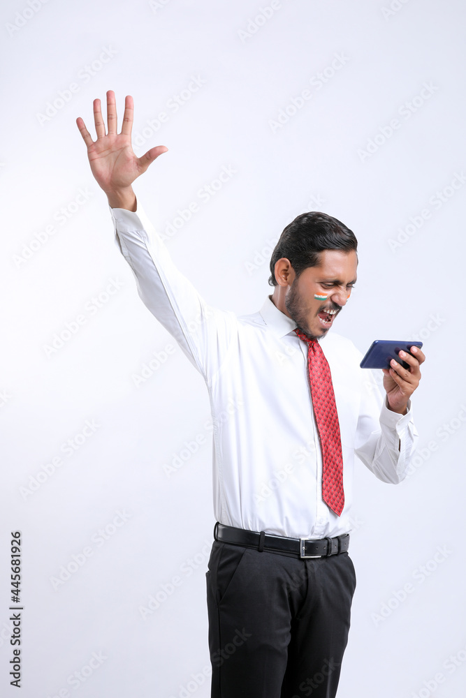 young indian man giving shocking expression after seeing smartphone. young indian man giving shocking expression after seeing smartphone.