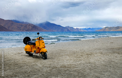 yellow scooter from bollywood movie parking at highest salt lake in the world with mountain background at Pangong Lake