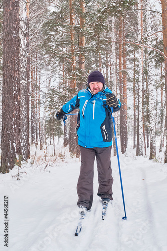 Mature male are cross-country skiing in snowy forest.