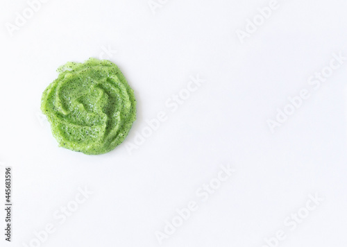 Gel texture with small particles of green scrub on a white background. Skin cleansing cream and copy space