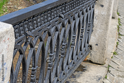 A fragment of a cast-iron fence of a city pond in close-up photo