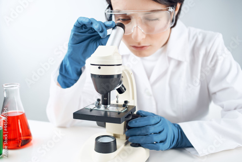 Woman in white coat laboratory microscope work science research
